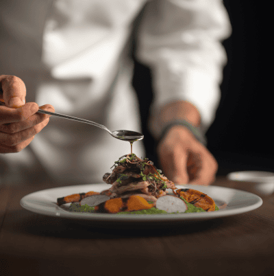 Chef garnishing dish with sauce