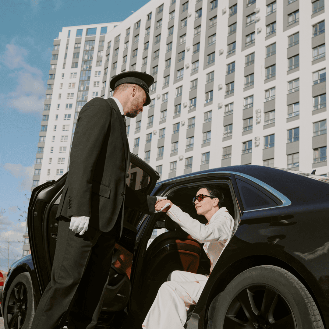 Chauffeur assisting woman into luxury car